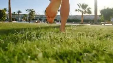 在绿草地上赤着脚奔跑的小女孩的腿。 年轻女孩光着脚走路的慢镜头